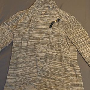 Maurice’s light gray cross sweater with metal clip